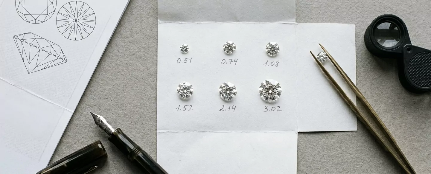 Sechs lose Round-Brilliant-Diamanten von 0,51 bis 3,02 ct auf weißem Parcel-Papier mit handschriftlichen Karatangaben — Messing-Pinzette, schwarze Belomo-Triplet-Lupe und Diamant-Skizzenbogen flat-lay.