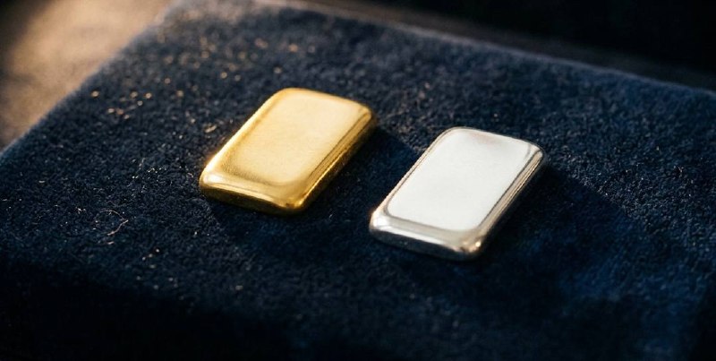 Goldbarren und Goldketten auf dunklem Samt