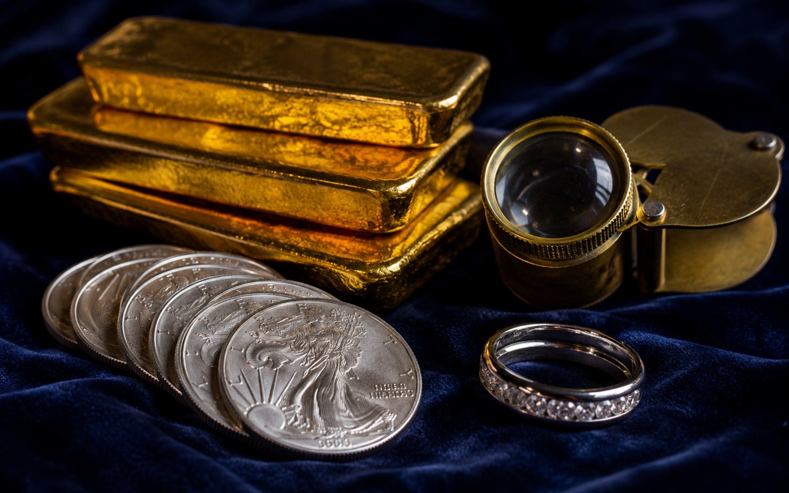 Goldbarren, Silberm&uuml;nzen und ein Diamantring auf blauem Samt, Edelmetallpreise