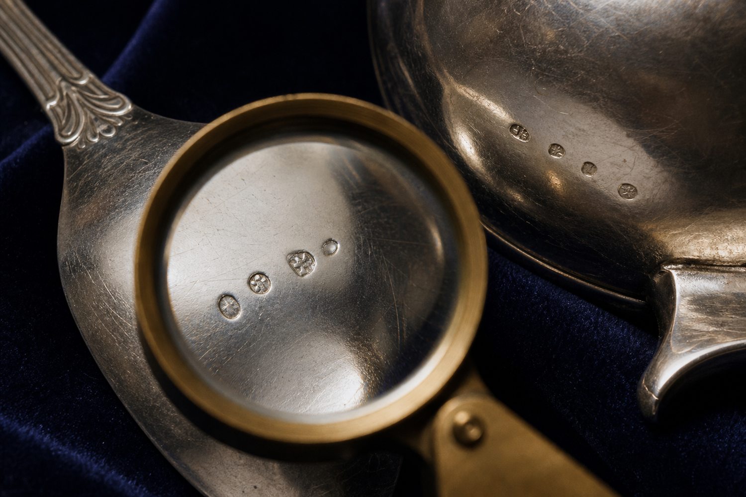 Silberpunzen auf der Unterseite eines L&ouml;ffels und einer Kanne werden mit einer Lupe gepr&uuml;ft &ndash; Silber-Punzen Bewertung K&ouml;ln