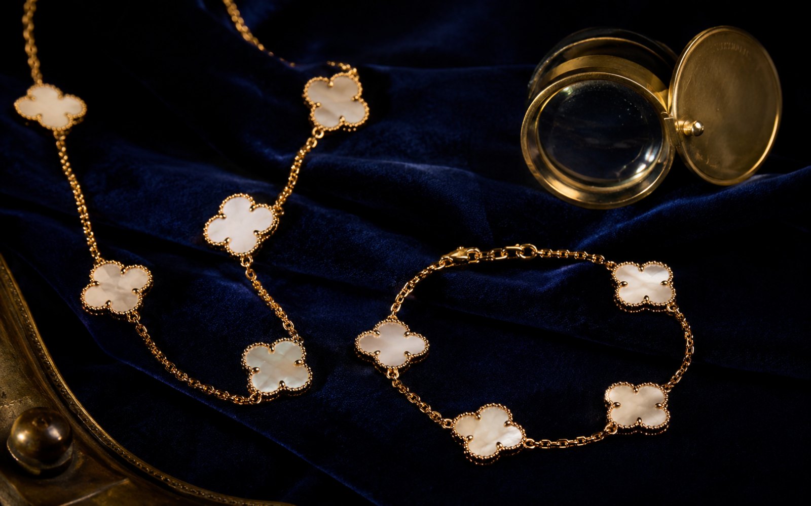 Van Cleef & Arpels Alhambra-Kette und -Armband mit Kleeblattmotiv auf blauem Samt mit Lupe